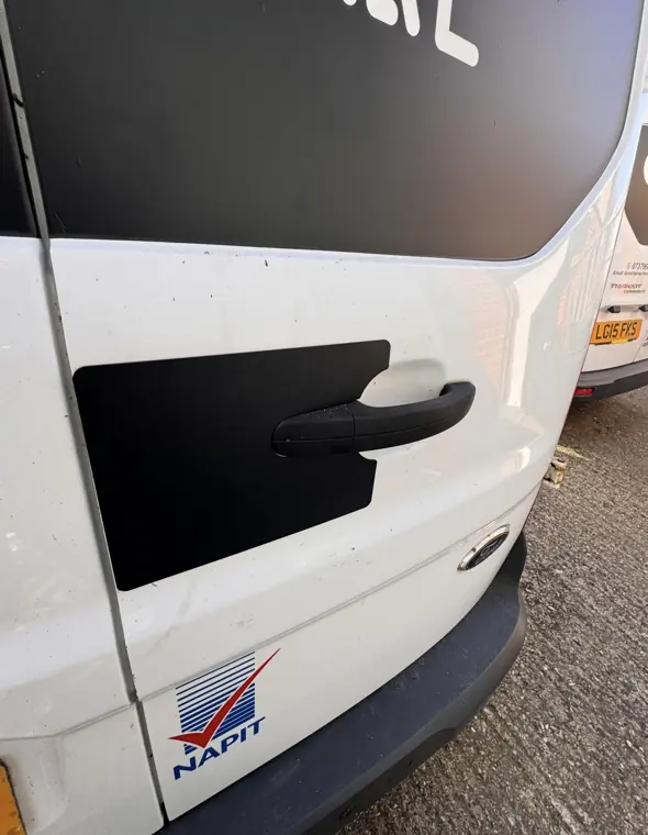 Black external plate fitted around a white van rear-door handle