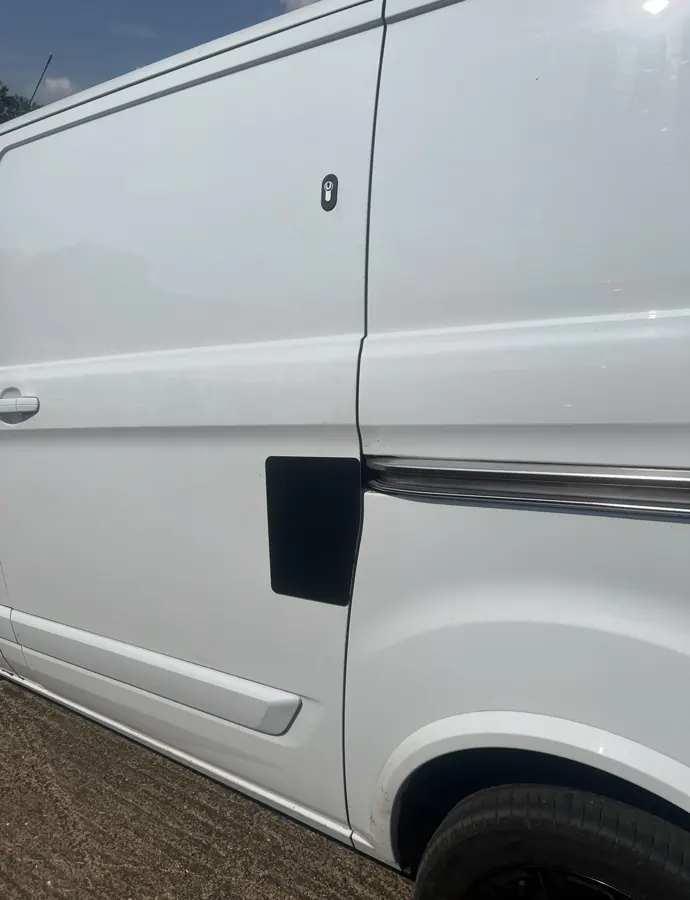 Wider view of repaired white van sliding door with black protective plate