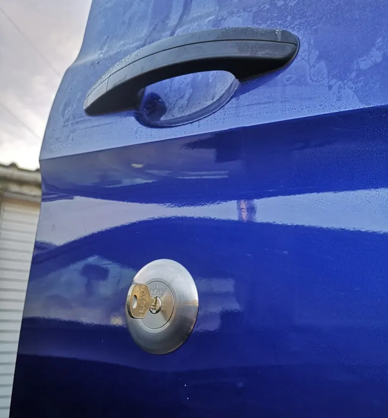 Blue van door with round replacement security cylinder and key inserted