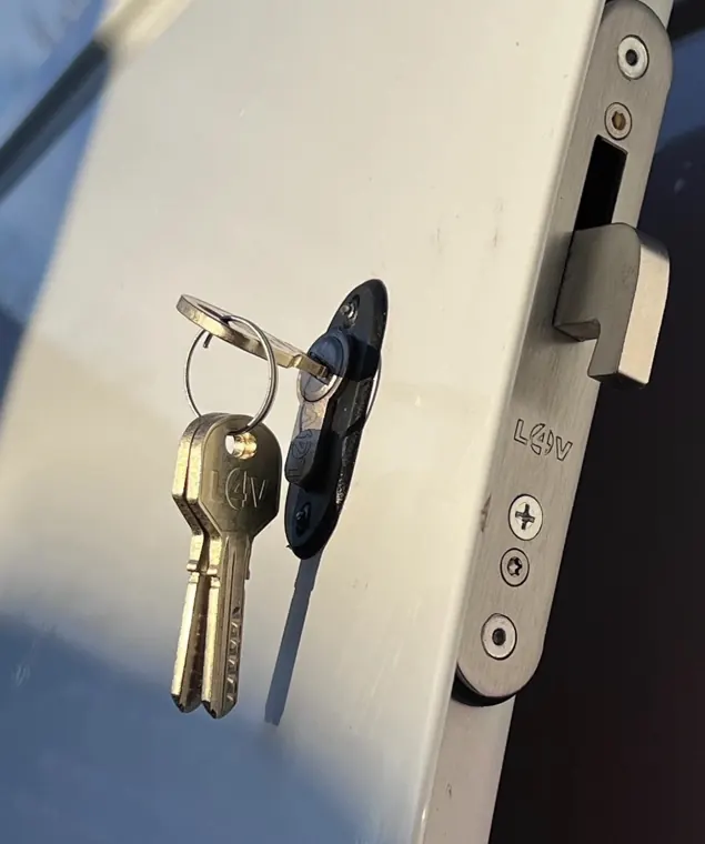 Silver hooklock plate and key on white van door
