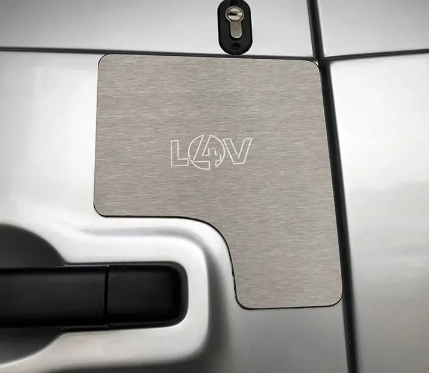 Stainless steel external repair cover plate installed beside the lock on a van door