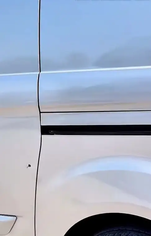 Close view of damaged van door panel before repair
